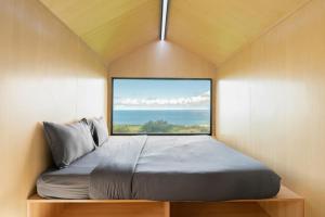 uma cama num pequeno quarto com uma grande janela em Bobocabin Umarato, Sumba em Waikabubak