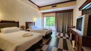 a hotel room with two beds and a flat screen tv at Pattaya Garden Resort in North Pattaya