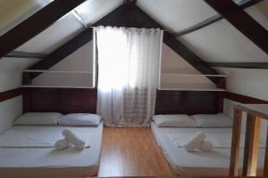 two beds in a attic room with a window at Panawan Cinco in General Luna