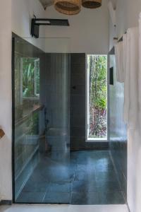 a bathroom with a shower and a toilet and a window at Oka Maraú I Charming Bungalows in Marau