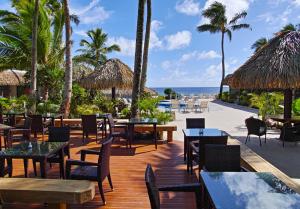 un restaurante en la playa con mesas y sillas en Club Raro Resort- Adults Only en Rarotonga