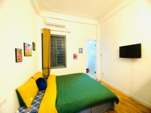 a bedroom with a green and yellow bed and a television at Hanoi Sunrise Homestay Long Biên in Hanoi