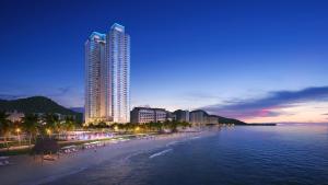 een uitzicht op een strand in de nacht met een hoog gebouw bij A La Carte Ha Long Bay Hotel in Ha Long