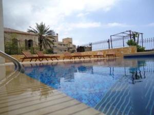 a swimming pool with benches and a volley ball court at Siena Hotel in Jounieh