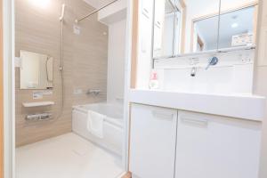 ein weißes Badezimmer mit einem Waschbecken und einem Spiegel in der Unterkunft V の Boutique House in Osaka