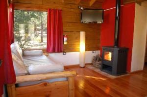 een kamer met een bed en een houtkachel bij Cabañas Bosques del Sol in Villa Giardino