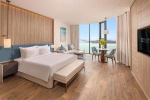 a bedroom with a large bed and a living room at A La Carte Ha Long Bay Managed by TASECO in Ha Long