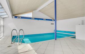 an indoor swimming pool with blue water in a building at Amazing Home In Bjert With House Sea View in Binderup Strand