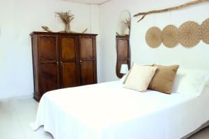 Schlafzimmer mit einem weißen Bett und einem Holzschrank in der Unterkunft Playa Centro Apartamento Equipado in Santa Marta