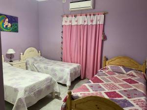 um quarto com 2 camas e cortinas cor-de-rosa em Hermosa Casa con Quincho y pileta em La Banda