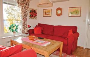 a living room with a red couch and a coffee table at Nice Home In Kil With House Sea View in Säbytorp