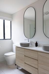 a bathroom with two sinks and a toilet and two mirrors at Nornalup Riverside Chalets in Nornalup