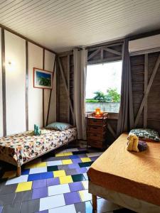 Zimmer mit 2 Betten und einem Fenster in einem Zimmer in der Unterkunft Charmante villa créole climatisée, jardin tropical et piscine privés in Lamentin