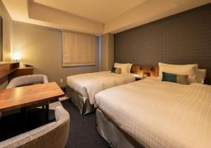 a hotel room with two beds and a table at Tokyu Stay Sapporo Odori in Sapporo