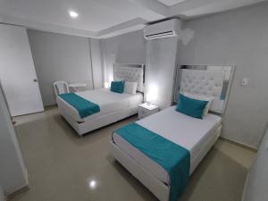 Dos camas en una habitación de hotel con azul y blanco en CASA BELLAMARE, en Cartagena de Indias