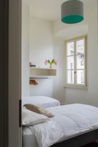 een witte slaapkamer met 2 bedden en een raam bij Villa Perpenti in Pianello Del Lario