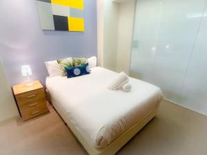 a bedroom with a white bed with a night stand at Melbourne City Central Apartment - 296 in Melbourne
