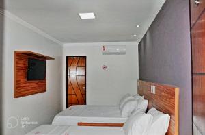 a bedroom with two beds and a wooden headboard at Hotel Center in Feira de Santana