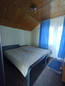 1 dormitorio con 1 cama con cortinas azules y techo en Punct Gastronomic Local Acasa la Vero, en Schiuleşti