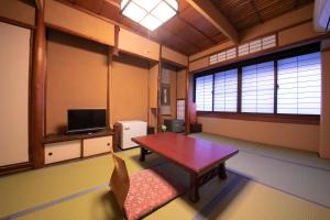 a living room with a table and a tv at Ohanabo in Kyoto