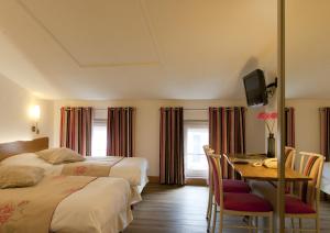 um quarto de hotel com duas camas, uma secretária e uma mesa em Logis Le Cheval Rouge em Sainte-Menehould