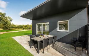 een zwart huis met een tafel en stoelen op een patio bij 3 Bedroom Awesome Home In Ringkbing in Ringkøbing