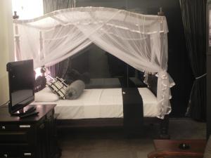 a bedroom with a canopy bed with white curtains at Amanda Beach Villas in Unawatuna