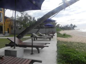 a row of benches with umbrellas on the beach at Amanda Beach Villas in Unawatuna
