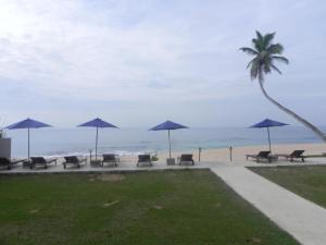 a row of chairs and umbrellas on the beach at Amanda Beach Villas in Unawatuna