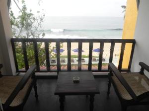 a balcony with a table and chairs and the ocean at Amanda Beach Villas in Unawatuna