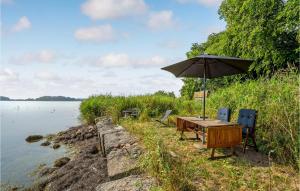 a table and chairs with an umbrella next to the water at 1 Bedroom Beautiful Home In Bandholm in Bandholm
