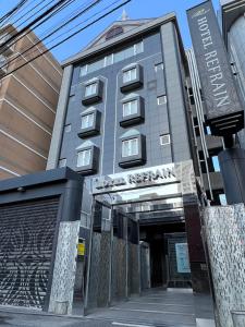 東京にあるHOTEL REFRAINの目の前に看板が立つ高い灰色の建物