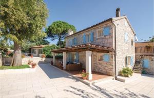 une maison en pierre avec des fenêtres bleues et un arbre dans l'établissement Nice Home In Tinjan With Jacuzzi, à Tinjan