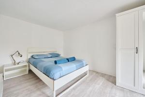 a white bedroom with a bed with blue pillows at Le Transvaal : À deux pas du centre. in Dijon