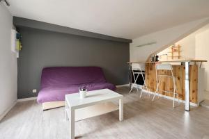 a living room with a purple couch and a table at Le Transvaal : À deux pas du centre. in Dijon