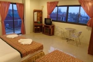 1 dormitorio con 2 camas, TV y mesa en G&B Guesthouse en Patong