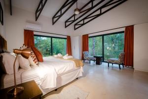 a bedroom with a large bed and large windows at Gem In The Bush Lodge in Hoedspruit