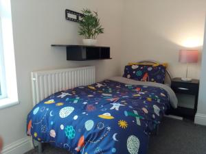 um quarto com uma cama com um edredão azul em Luxury House Near City Center Hospital &Superstore em Carlisle