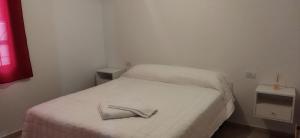 a small white bed with a pair of shoes on it at Los Olivos Apart in San Rafael