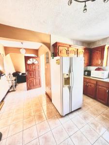 a kitchen with a white refrigerator and wooden cabinets at 2 Bed Apartment at the Hideaway in St Mary