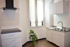 una cucina con armadi bianchi, lavandino e pianta di Appartamento magico nel centro del borgo L'ancora. a Laigueglia