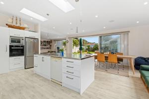 a kitchen with white cabinets and a dining room at Matapouri Family Retreat - Matapouri Holiday Home in Matapouri