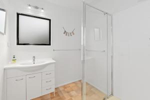 een witte badkamer met een wastafel en een douche bij Matapouri Family Retreat - Matapouri Holiday Home in Matapouri