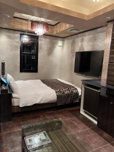 1 dormitorio con 1 cama y TV de pantalla plana en HOTEL Shuffle en Tokio
