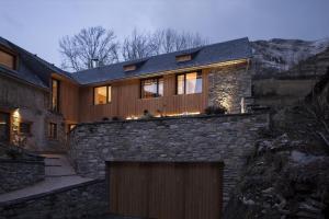 a house with a stone wall and a garage at Maison Seignou in Azet