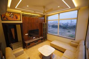 een woonkamer met een bank en een groot raam bij Taj Sojourn in Agra