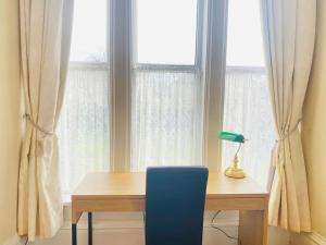 escritorio con silla azul frente a una ventana en Spacious Flat In a Victorian House - Free Parking en Bradford