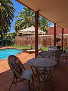 a patio with a table and chairs next to a pool at Tuileries at De Bortoli Rutherglen in Rutherglen