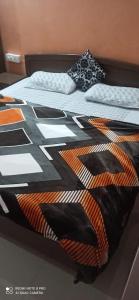 a bed with a black and orange comforter on it at Mountain and Moon, Dharamkot in Dharamshala