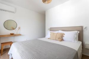 a white bedroom with a large bed with a mirror at SUNSET220 spetses in Spetses